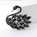 Macro shot of silver-tone swan brooch set with faceted black crystals on white surface - Black