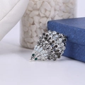 Macro shot of silver hedgehog brooch with white and green crystals on blue box - Antique Silver