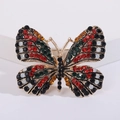 Detailopname van vlinderbroche met kleurrijke strassteentjes op gouden legering - Rood