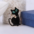 Detail van de zwarte emaille kattenbroche met groene edelstenen ogen op goud - Zwart