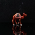 Macro shot of colorful enamel camel brooch with sparkling rhinestones on black background - Orange