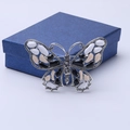 Detalle macro de broche de mariposa esmaltada con diamantes en estuche de joyas - Negro