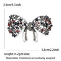 Detailed view of silver bow brooch with colorful rhinestones measuring 5.6cm by 3.3cm - Red