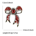Broche de lazo vintage con cristales rojos y perlas sobre fondo blanco neutro - Rojo