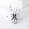 Vintage style spider brooch with grey faux pearl and green crystal eyes on a white pedestal - Grey Style