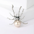 Vintage spider brooch with champagne pearl and green crystal eyes on a white pedestal - Pink Style