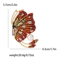 Elegant gold butterfly brooch with orange rhinestones and a large round pearl drop - Red