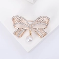 Elegante spilla a fiocco traforata oro rosa con cristalli e una perla bianca pendente - Oro