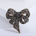 Elegant hollow bow brooch pin with colorful rhinestones in vintage bronze finish on white base - Colorful