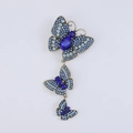Dettaglio di spilla con tre farfalle di cristallo blu in finitura oro vintage - Blu