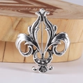 Macro detail of a vintage silver fleur-de-lis brooch on a wooden stand - Silver