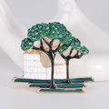 Detailansicht einer vergoldeten Baumbrosche mit grünen Kristallen und Architektur auf Handmodell - Grün