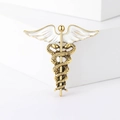 Dettaglio della spilla caduceo dorata con squame di serpente e ali in smalto bianco - Bianco