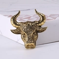 Detailed macro view of retro golden bull head brooch with carved texture and spiral horns - Antique Gold