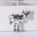 Macro shot of vintage silver cow brooch with heart patterns on a white jewelry display box - Silver