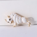Macro shot of vintage ox brooch showing white enamel finish and gold-plated details - White