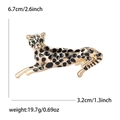 Spilla a leopardo dorata con smalto nero e occhi in gemme verdi su sfondo bianco - Oro