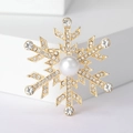 Vista macro de un broche de copo de nieve dorado con perlas y diamantes de imitación - Dorado