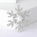 Detalle del broche de copo de nieve plateado con pedrería brillante y perla blanca central - Plateado