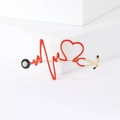 Détail de la broche stéthoscope dorée avec cœur en émail rouge et ligne d'électrocardiogramme - Tête Noire Cœur Rouge (MM-BR-2097) / Rouge