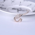 Détail de la broche crevette en or rose avec strass blancs brillants sur marbre - Blanc