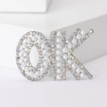 Detailed view of OK letter brooch with white faux pearls and shimmering AB rhinestones - Silver