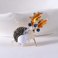 Dettaglio ravvicinato di una spilla a riccio con strass blu e accenti di foglie d'oro - Giallo