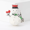Dettaglio della spilla a pupazzo di neve in smalto con cappello rosso e sciarpa verde - Bianco