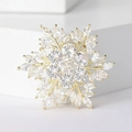 Elegante broche de copo de nieve dorado con cristales de circón en fondo blanco - Dorado