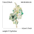 Elegante spilla a fiore di rosa con zirconi verdi e finitura dorata su sfondo bianco - Verde