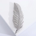 Detalle macro de un broche de pluma plateado con incrustaciones de circonitas brillantes - Plateado