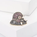 Dettaglio macro della spilla a cappello retrò con strass rosa e fiori in metallo - Marrone
