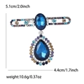 Spilla elegante in lega con gemme di vetro blu e strass colorati su sfondo bianco - Blu