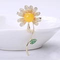 Close-up of elegant daisy brooch with amber-like center and micro-pave zircons - Gold