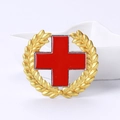 Enamel red cross brooch with golden laurel wreath detail on a white ceramic tray - Red