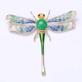Détail macro d'une broche libellule avec pierre verte et ailes en émail coloré - Bleu