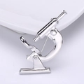 Detail of silver microscope brooch with polished finish and secure pin back on white base - Silver