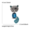 Elegante broche de gato con cristal azul ovalado y diamantes grises sobre blanco - Azul