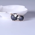Detail view of two black sheep brooches with knitting needle accents on a white shell plate - Gray Sheep Set (MM-BR-2074) / Gray
