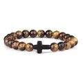 Detailed macro shot of 8mm tiger eye stone beads with a matte black cross pendant - Tiger's Eye