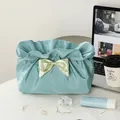 Blue pleated makeup bag with green satin bow on a bright white table setting - Fresh Blue