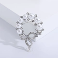 Elegant silver wreath brooch featuring white pearls and rhinestone bow on a white pedestal - Silver