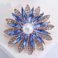 Macro detail of sun flower brooch with sky blue crystals and white pearl center - Blue