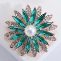 Macro view of emerald crystal sunflower brooch with center pearl and rose gold plating - Green