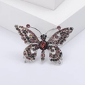 Elegante vlinderbroche met gekleurde kristallen op een zilveren voet en wit podium - Paars