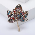 Detail of vintage leaf brooch with multi-color rhinestones and antique gold finish - Colorful