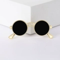 Detalle de un broche de gafas de sol chapado en oro con circonitas y toques negros redondos - Dorado