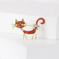 Detailed view of creative orange enamel cat brooch with rhinestones on a white stand - Red