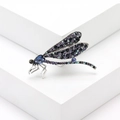 Detailopname van de libellebroche met paarse strass en donkerblauwe kristallen op metaal - Inktblauw