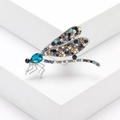 Prachtige zilveren libelspeld met veelkleurige kristallen op een wit geometrisch blok - Blauw